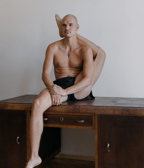 Man performing a controlled strength exercise in a dark, minimalist setting.